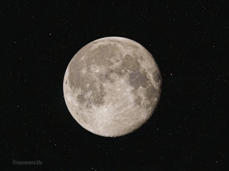 A detailed full moon with visible craters and maria, set against a dark, star-filled night sky.